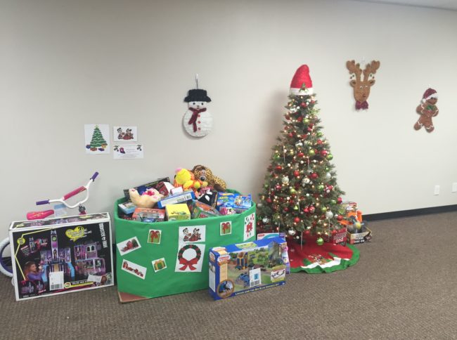 Dozens of holiday toys around the tree FreshPoint Dallas ready to donate to The Family Place.